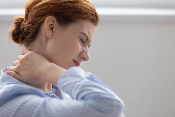 Woman experiencing physical stress, a sore neck.