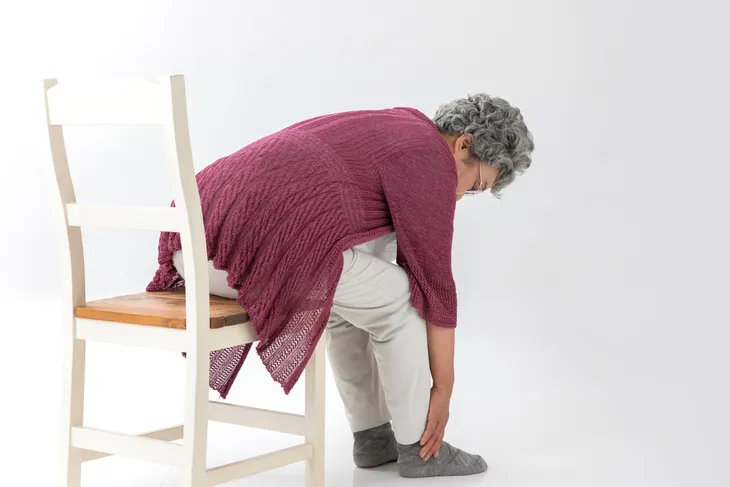 senior woman performing Lumbar Flexion exercise.