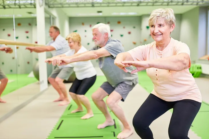 Seniors doing squats in the gym