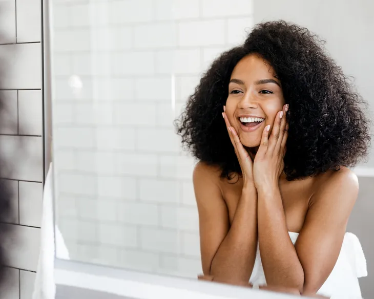 Woman looking in the mirror at healthy skin 
