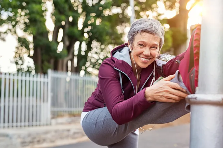 Senior woman stretching leg on pole