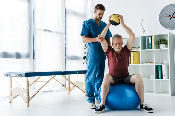 senior man doing overhead press with a medicine ball