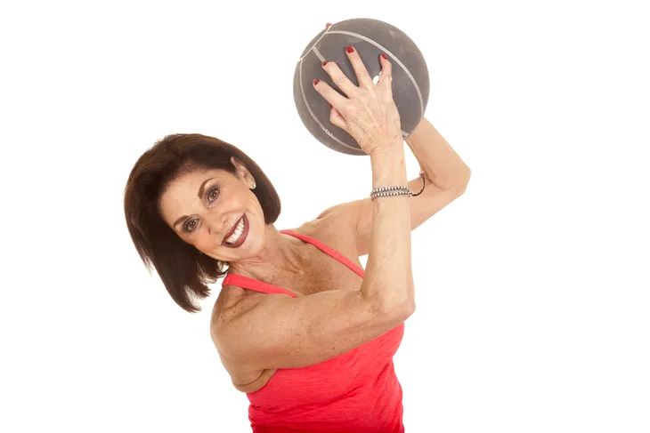 Senior woman holding medicine ball in the air