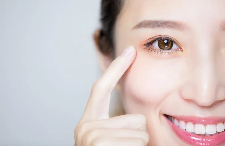 Woman pointing at her healthy eyes from mangoes