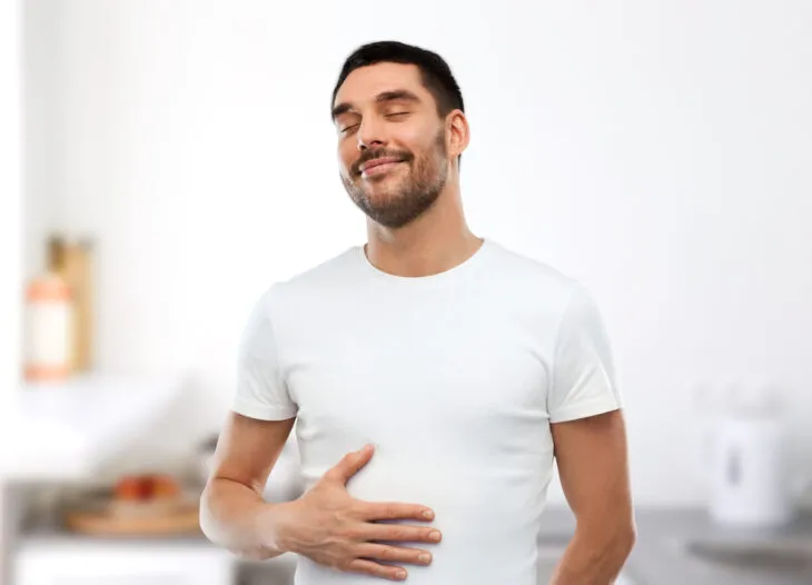 Man rubbing belly indicating happy digestion from magoes