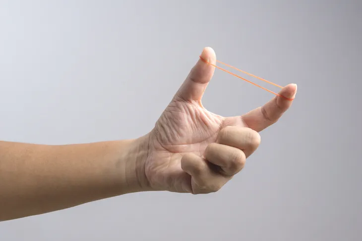 A Person With Two Hands Stretching A Rubber Band Stock